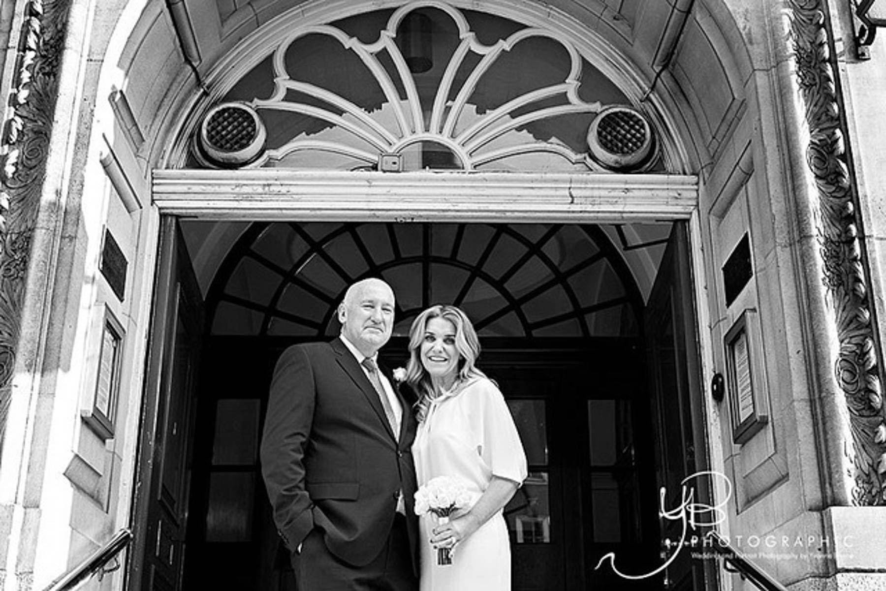 Black and white image of a bride and groom exit the Chelsea Old Town Hall after their Rossetti Room Wedding Ceremony.
