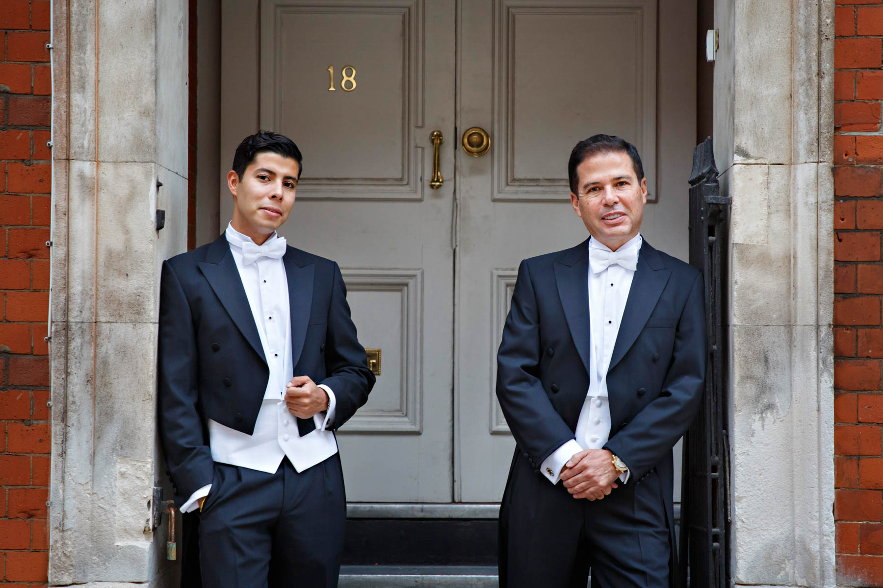 Two grooms in black tuxedos pose casually for their pre-wedding portraits, ahead of their Chelsea Register Office Wedding.