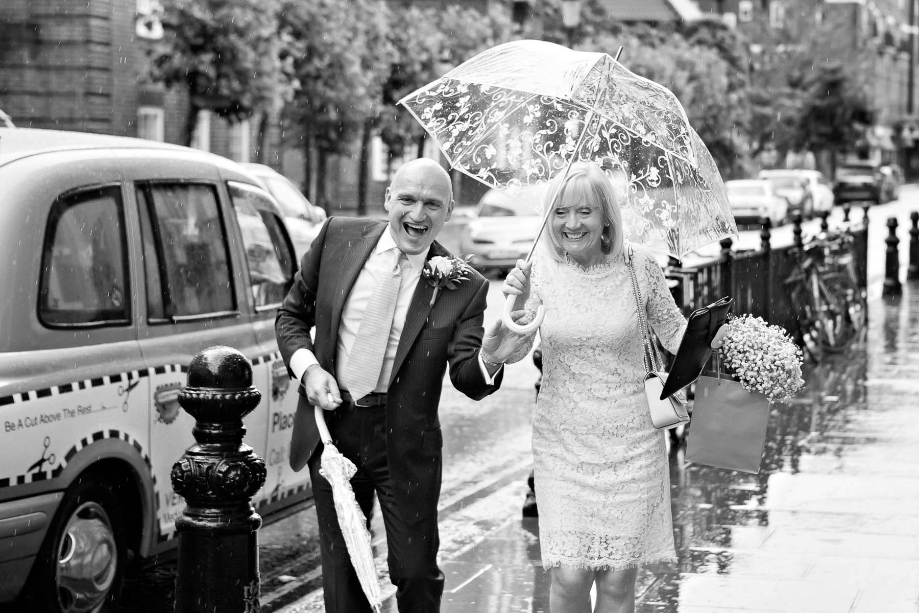 Handling rain on their wedding day, this couple grabbed a transparent umbrella for their ceremony at Chelsea Register office on the Kings Road. 