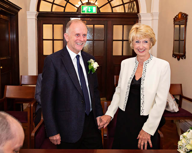 An older couple hold hands during their civil wedding ceremony at Chelsea Town Hall.