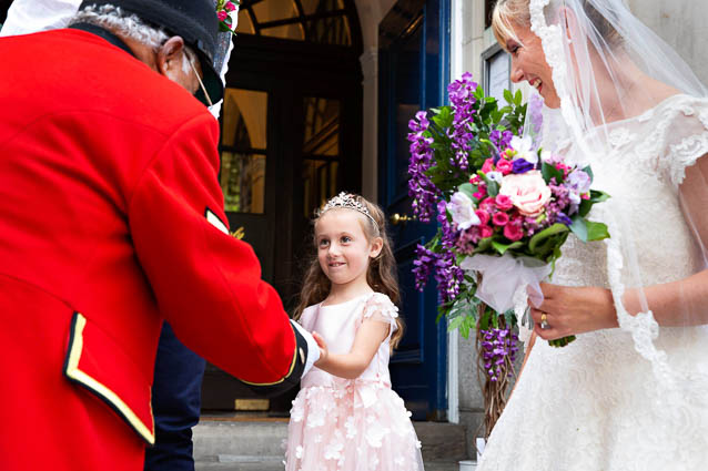 A bridesmaid meets a Chelsea Pensioner in his red uniform and black hat outside Chelsea Town Hall on the Kings Road, London.