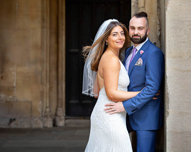 A bride in a white backless gown and veil poses for portraits with her new husband after their Chelsea Registry Office civil wedding in London.