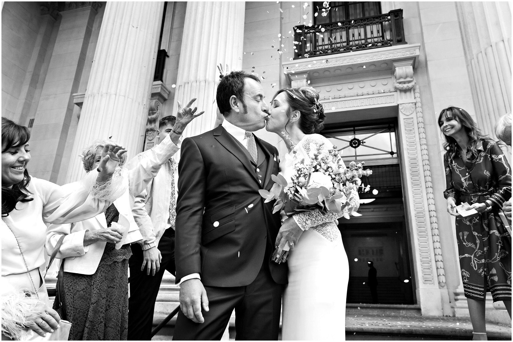 black and white photograph of bride and groom kissing on the steps of The Old Marylebone Town Hall
