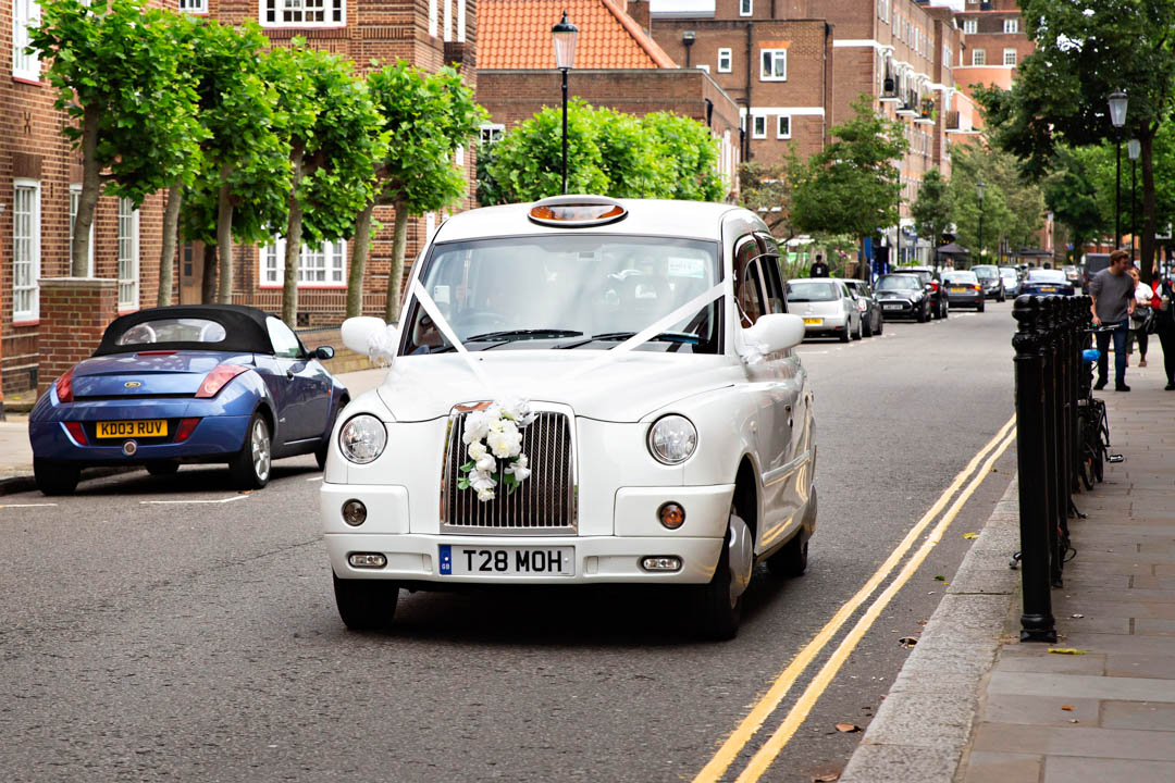A white wedding taxi rolls up to deliver a bride for her Brydon Room wedding ceremony at Chelsea Old Town Hall.