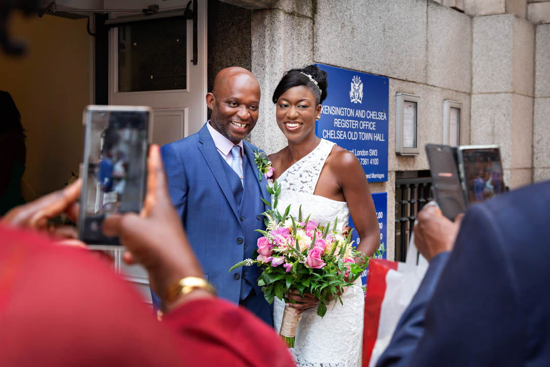 The bride and groom are photographed by their guests as they get ready to enter Chelsea Old Town Hall.