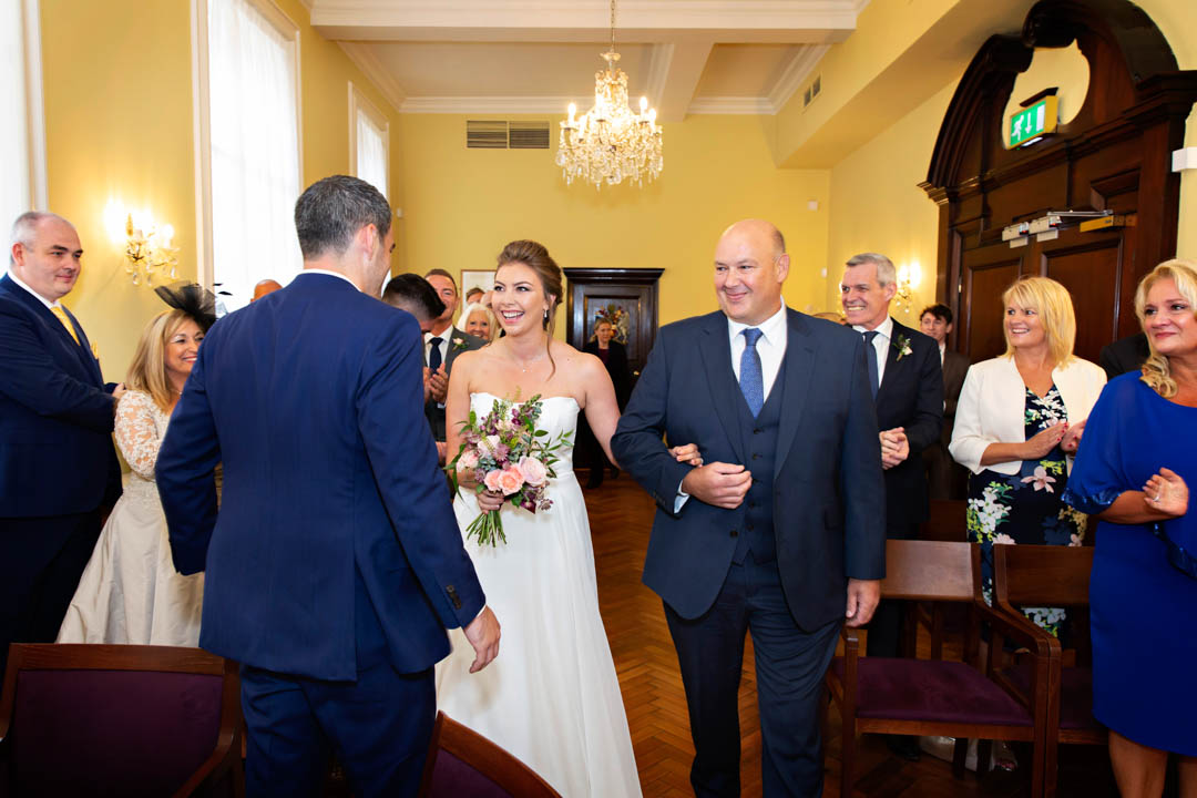 The father of the bride delivers the bride to the groom at the start of their wedding ceremony in the Brydon Room.