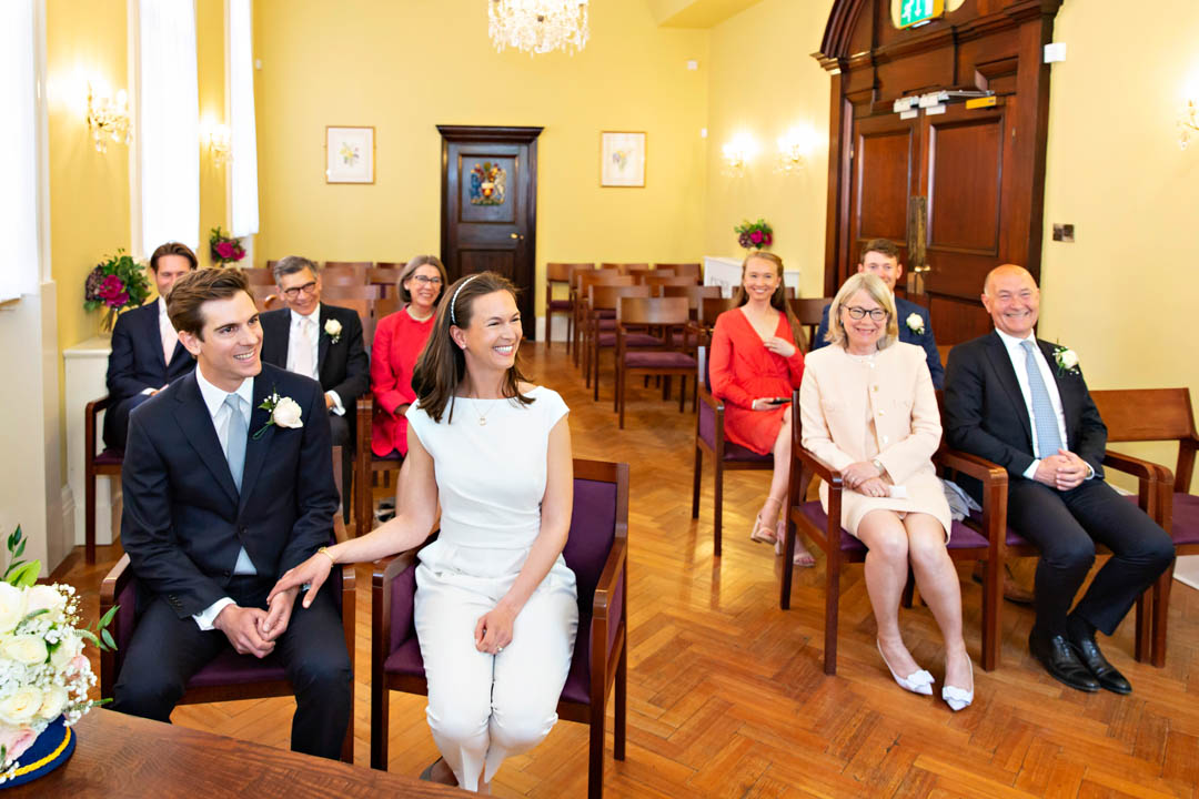 The wedding couple and their guests pay attention to the reader during their wedding ceremony.