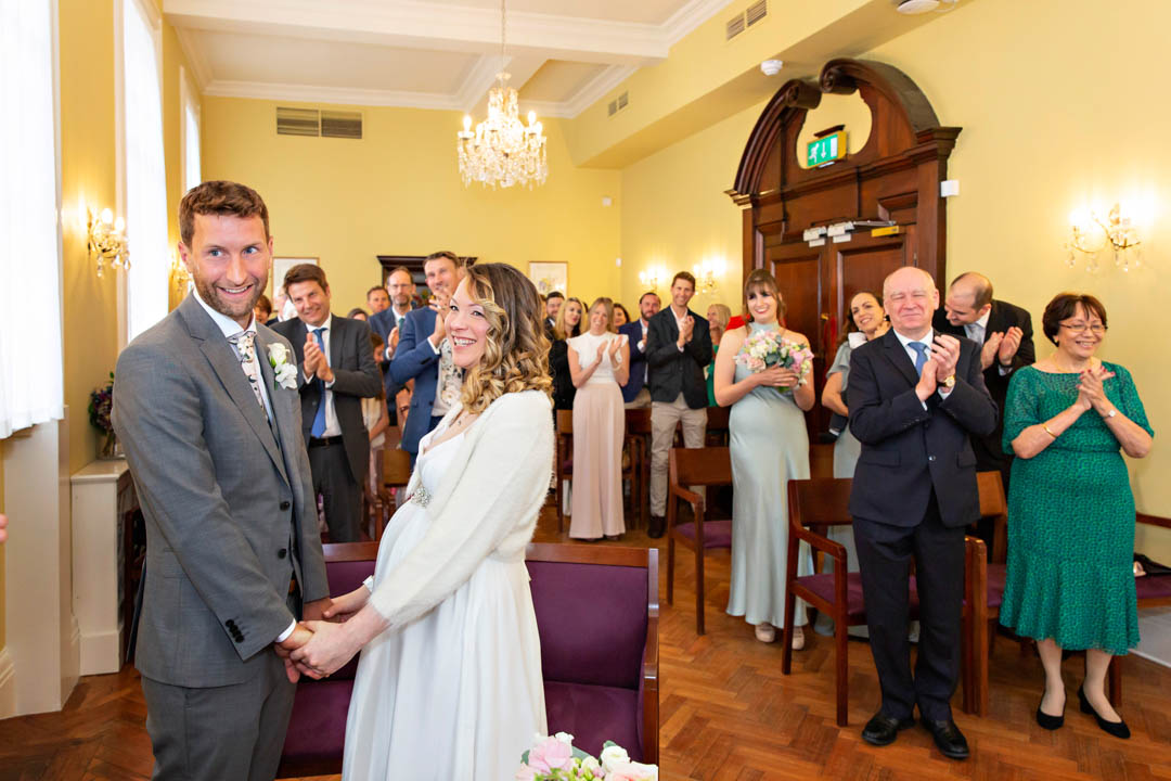 A bride and groom are applauded by their guests at the end of their wedding in the Brydon Room.