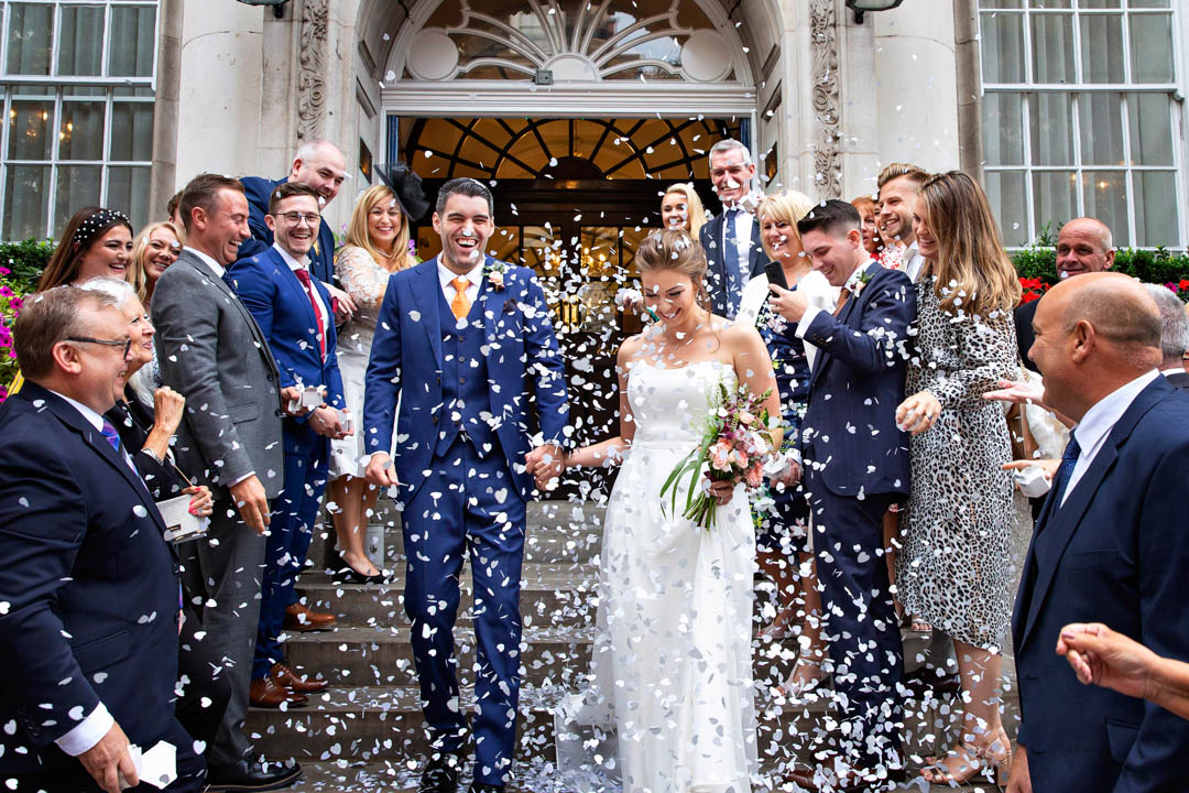 This wedding couple look delighted with how much confetti is being thrown at them on the steps of Chelsea Old Town Hall