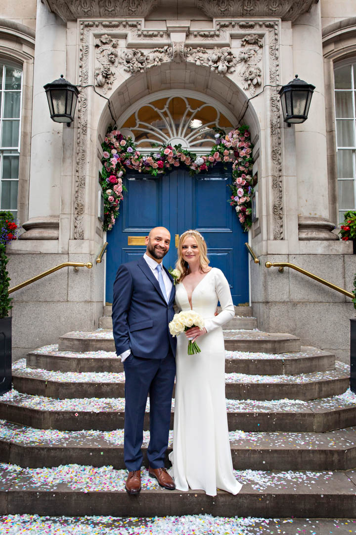 Full length portrait of a bride and groom on the steps of Chelsea Old Town Hall