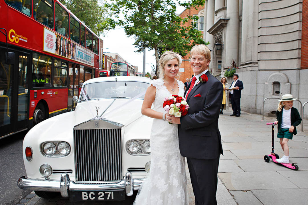 A bride and groom for their wedding portraits with their white vintage wedding rolls Royce on the Kings Road outside Chelsea Old Town Hall.