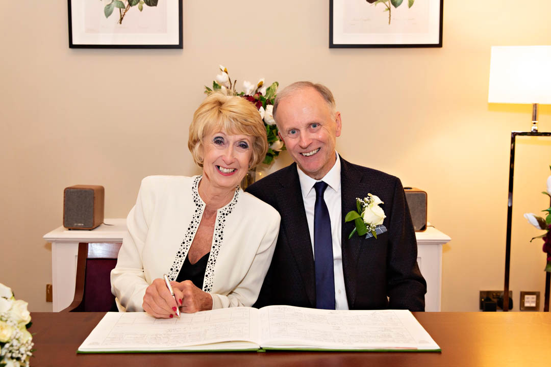 Bride and groom sign the wedding register during their elopement ceremony in the Harrington Room