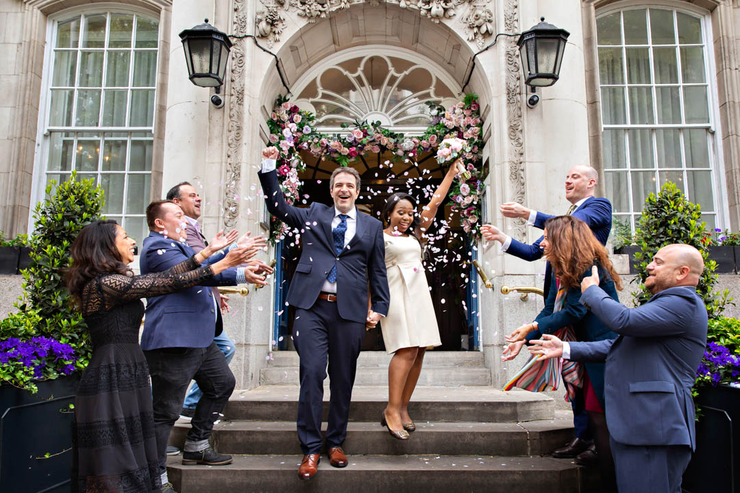 Bride and groom exit into a flurry of confetti on the steps of Chelsea Town Hall