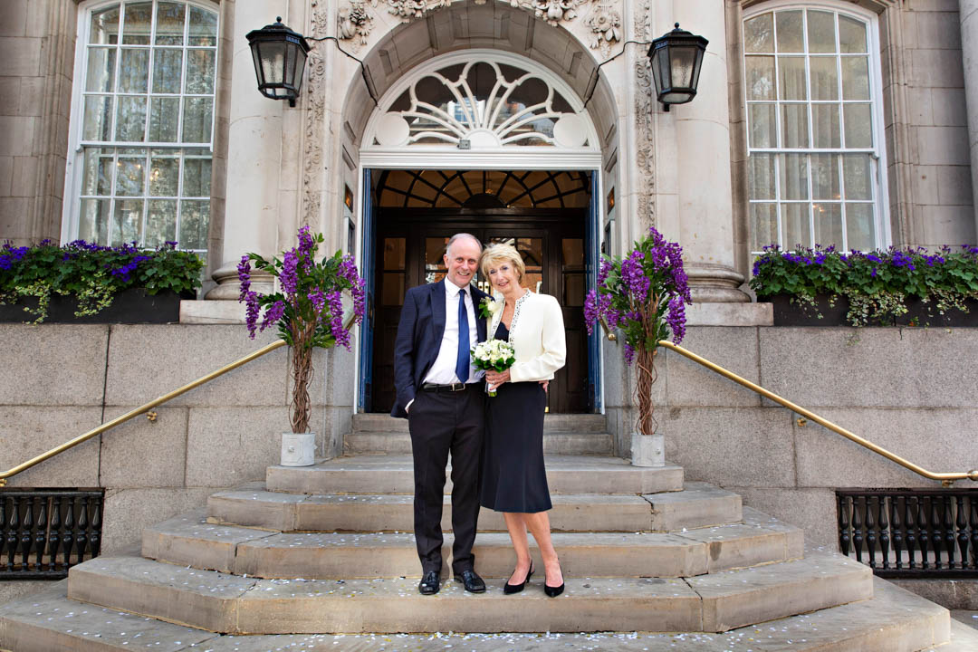 Bride and groom pose on the steps of Chelsea Register Office after getting married in the Harrington Room