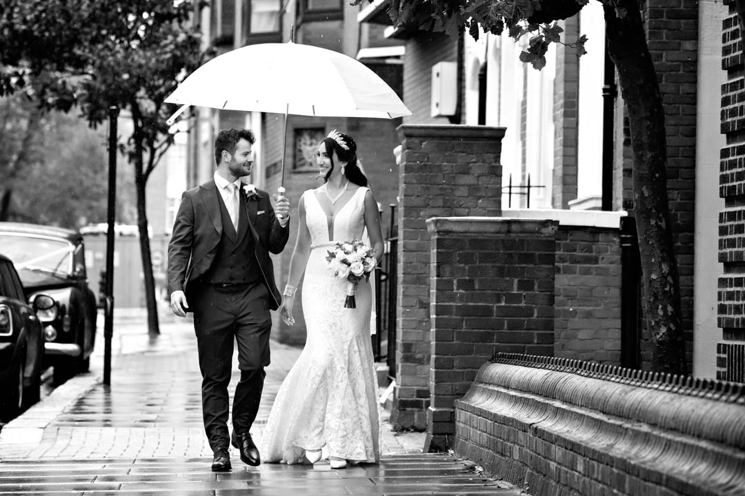 Glamorous bride in full length lace bridal lace gown walks with her groom after getting married in the Harrington Room.