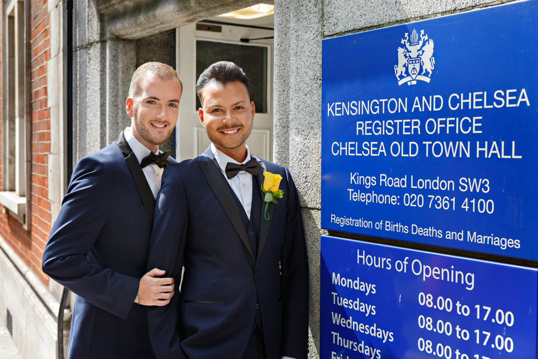 Two grooms wait outside Chelsea Old Town Hall before their Rossetti Room wedding.