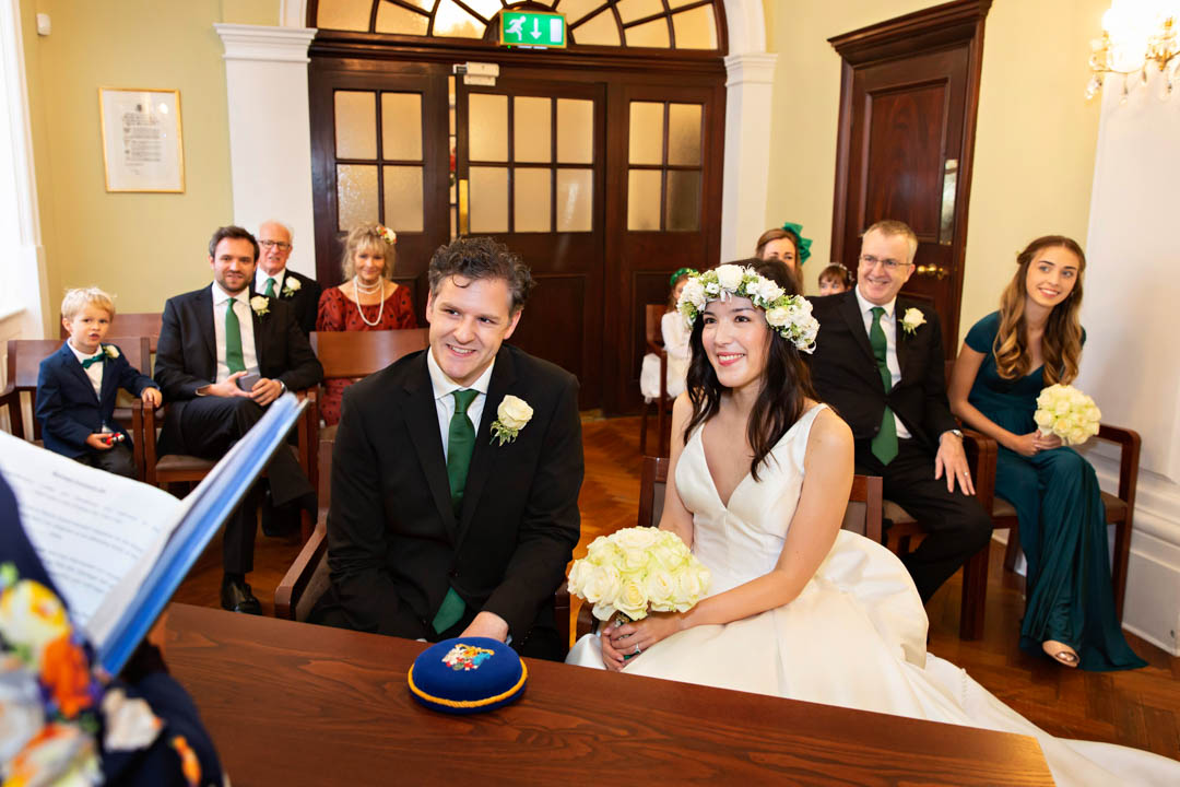 A bride and groom sit together smiling in the Rossetti Room during their marriage ceremony.