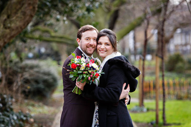 A bride and groom snuggle up together for a natural candid wedding portrait after their winter wedding at Southwark Register Office.
