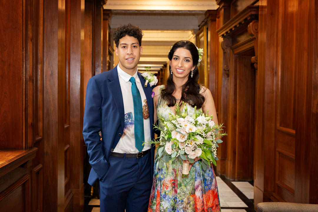 A bride in a floral dress poses with her groom before the start of her wedding to take place in the Knightsbridge room.