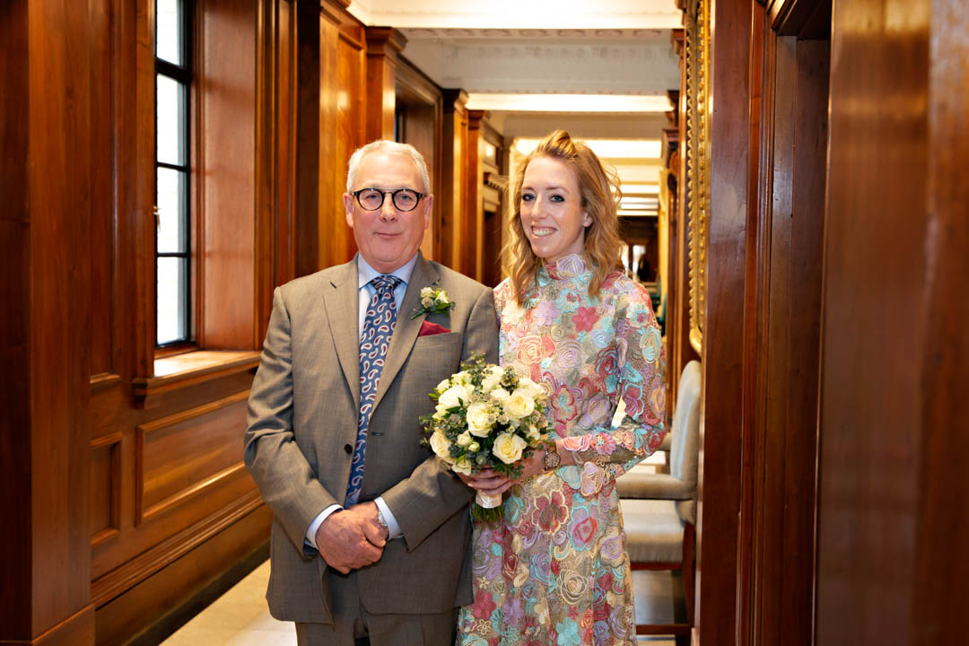 A bride waits with her father in the corridors of OMTH before walking into the Knightsbridge room for her wedding ceremony.