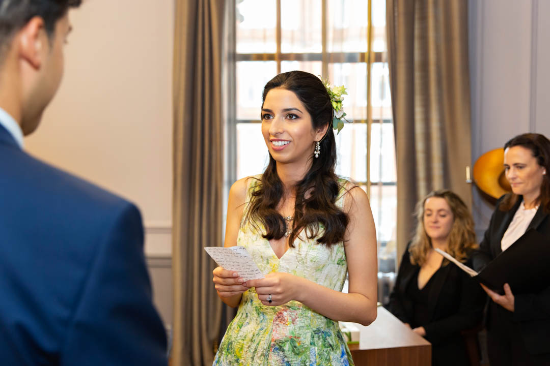 A bride reads handwritten vows to her groom in the Knightsbridge Room at Old Marylebone Town Hall