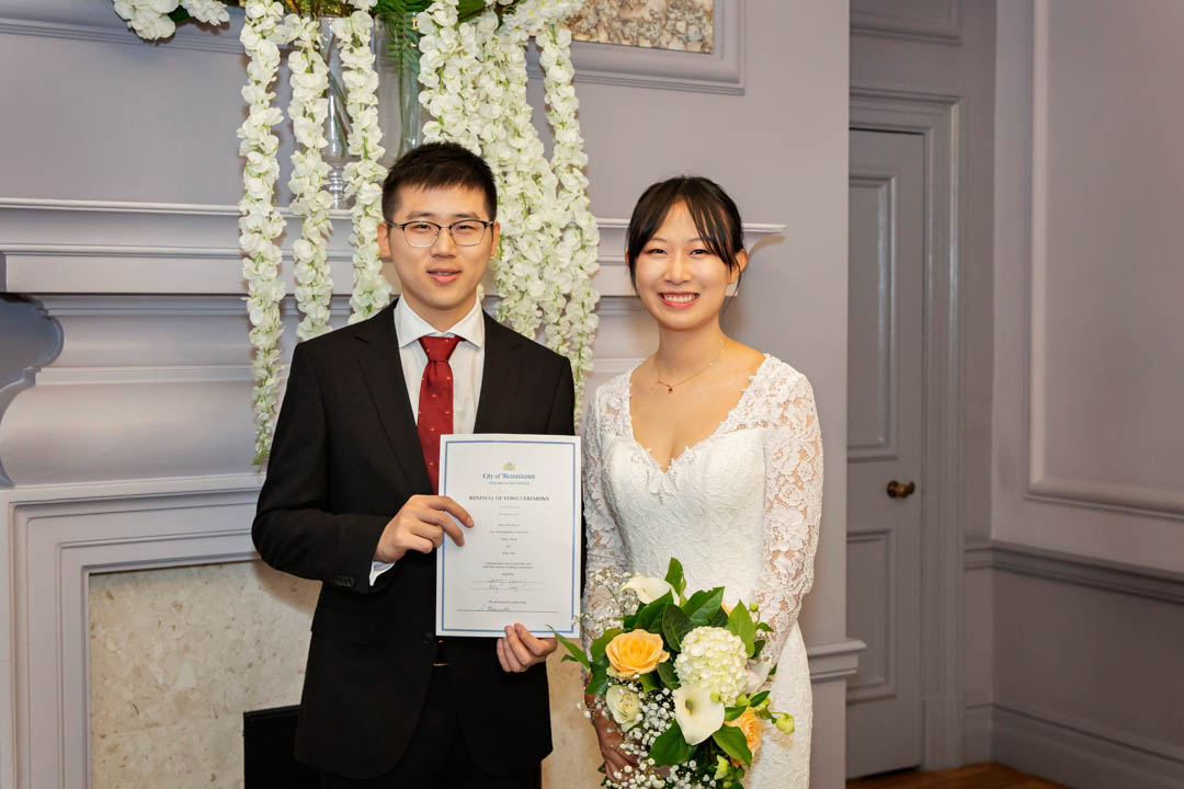 Bride and groom pose with their signed wedding schedule in the Knightsbridge Room