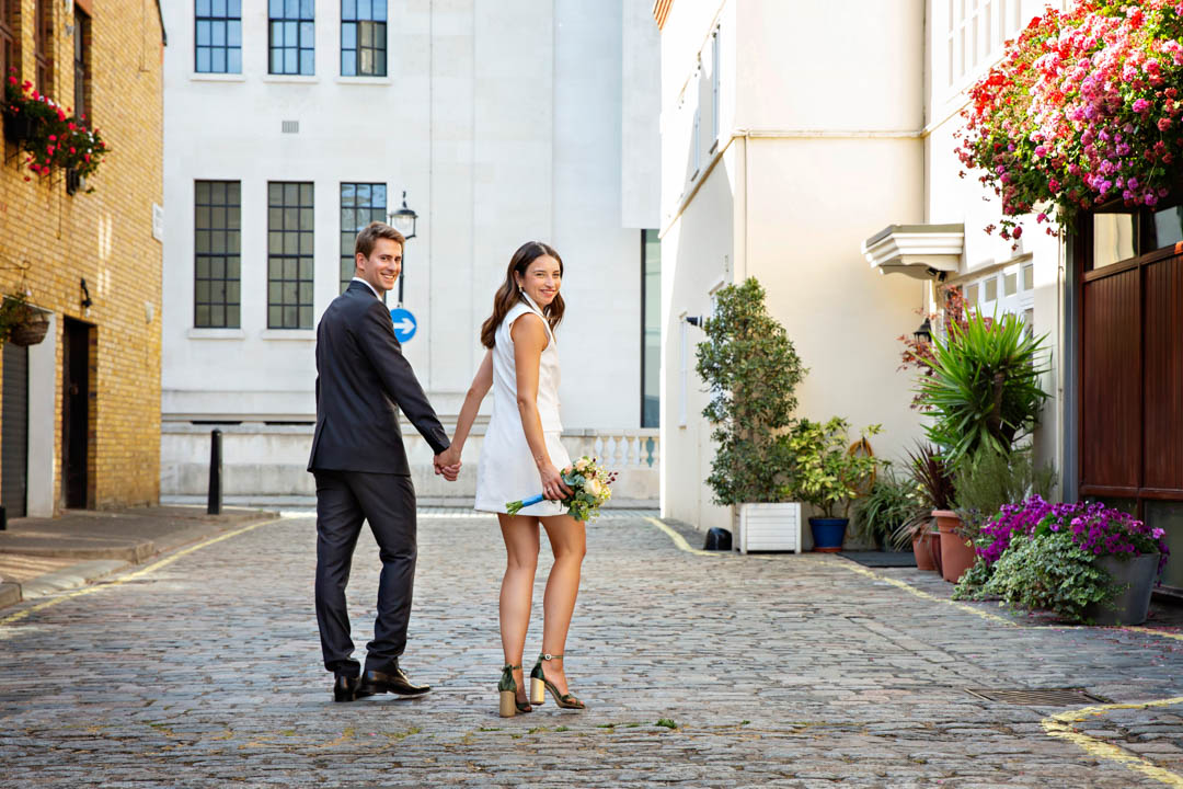 Bride and Groom walk along cobbled mews in Marylebone for their relaxed and natural wedding portraits