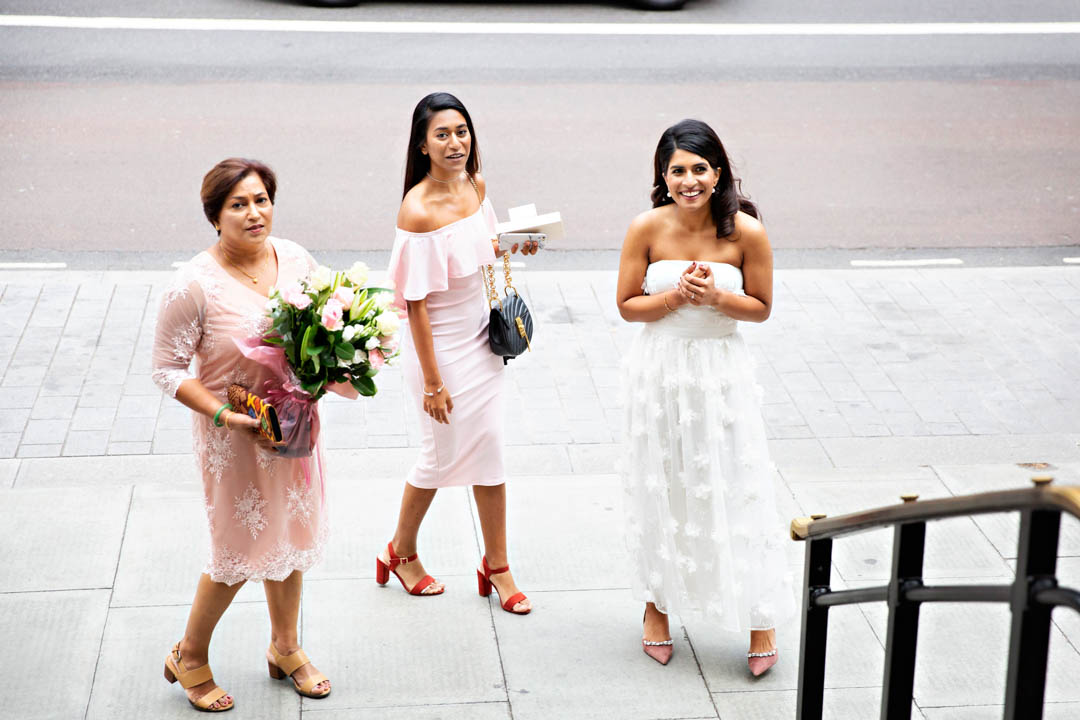 A bride looks excited as she arrives at the Old Marylebone Town Hall with her mother and sister.