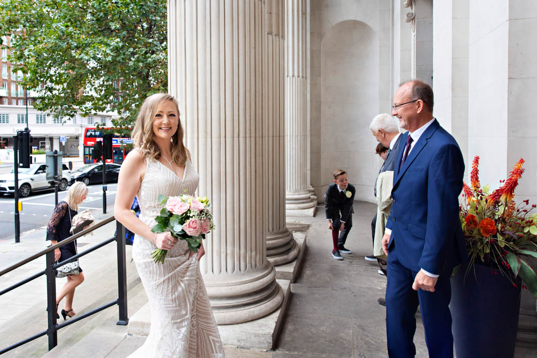 A bride looks happy as she arrives at the Old Marylebone Town Hall for her civil wedding ceremony.