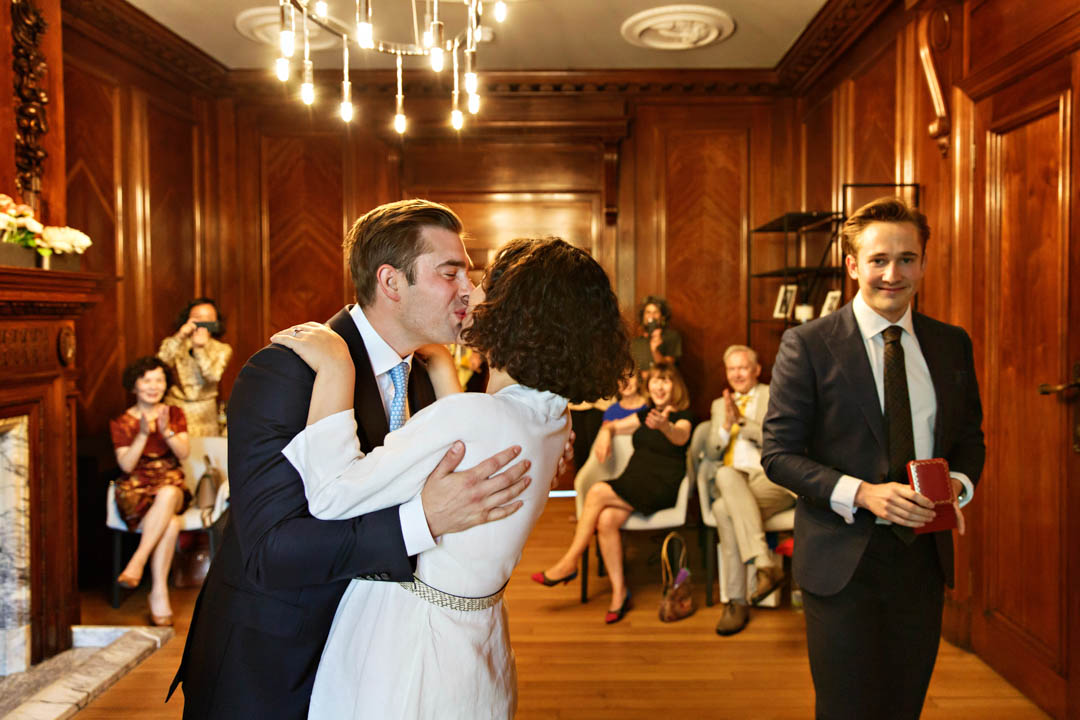 The groom nearly pushes the bride over as he passionately kisses her to celebrate exchanging vows in the Marylebone Room.