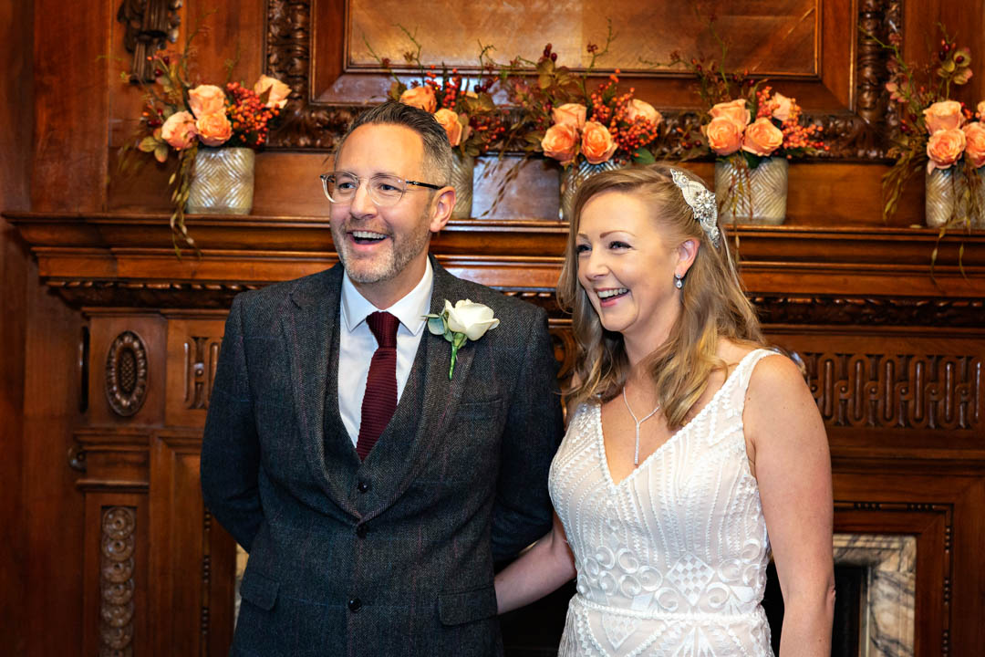 A bride and groom break into laughter during their wedding ceremony in the Marylebone Room.