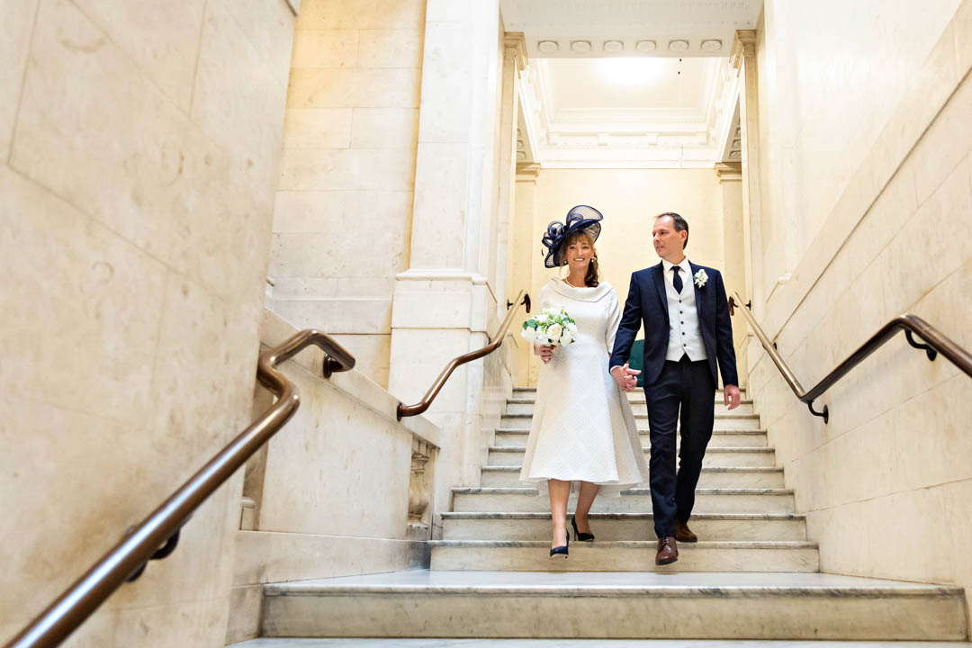 A bride and groom come walking down the steps of Westminster register office after their Marylebone Room civil wedding.