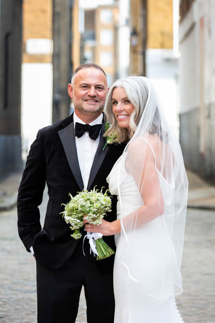 An elegant grey-haired bride and groom pose for a wedding portrait in a Marylebone Mews.