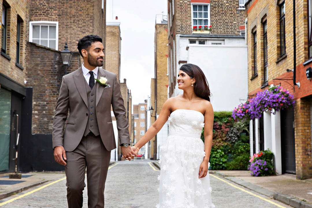 Newlyweds stroll through Marylebone cobbled mews holding hands.