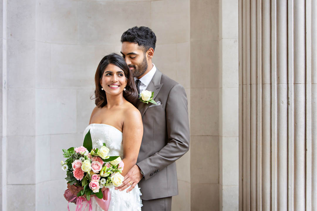 A bride and groom snuggle together for a romantic portrait after their register office wedding in the Marylebone Room.