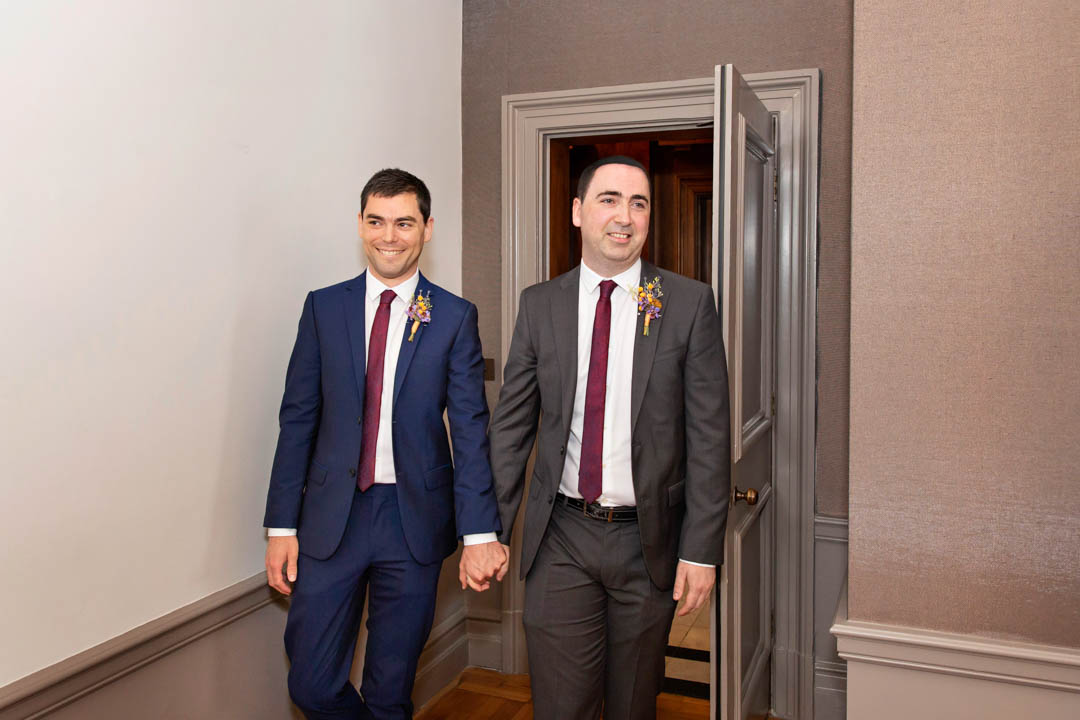 Two grooms enter the Mayfair Room together for their LGBTQ+ wedding ceremony in the Mayfair Room.