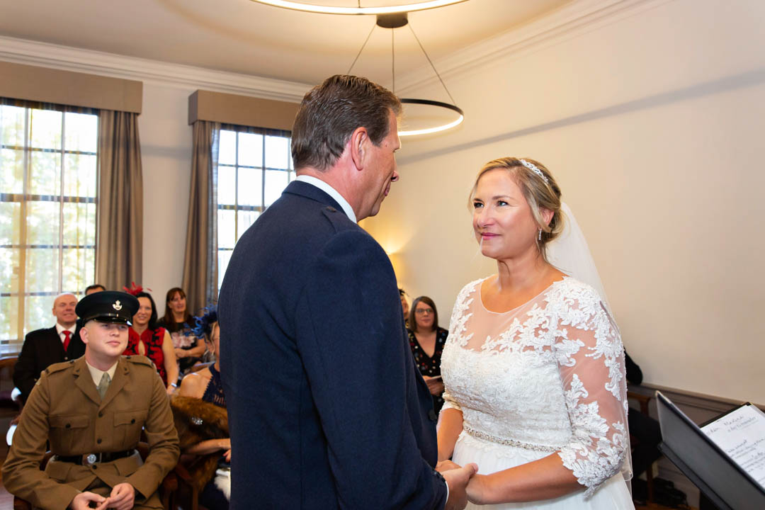 The bride intensely looks at the groom as they exchange wedding vows in the Mayfair Room at The Old Marylebone Town Hall.