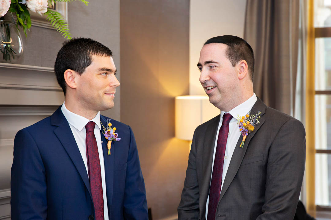Two grooms look intently at each other as they exchange wedding vows during their gay wedding ceremony in the Mayfair Room.