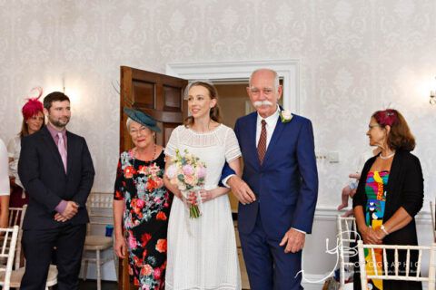 The father of the bride beams with pride as he walks the bride down the aisle at Morden Park House.