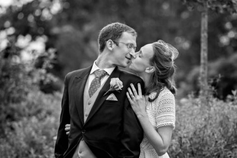 Black and white photograph of newlyweds kissing during their wedding portrait session at Morden Park House.