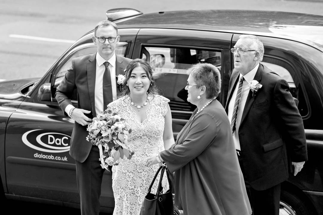 A bride and groom arrive at the Town Hall in a classes black London Taxi.