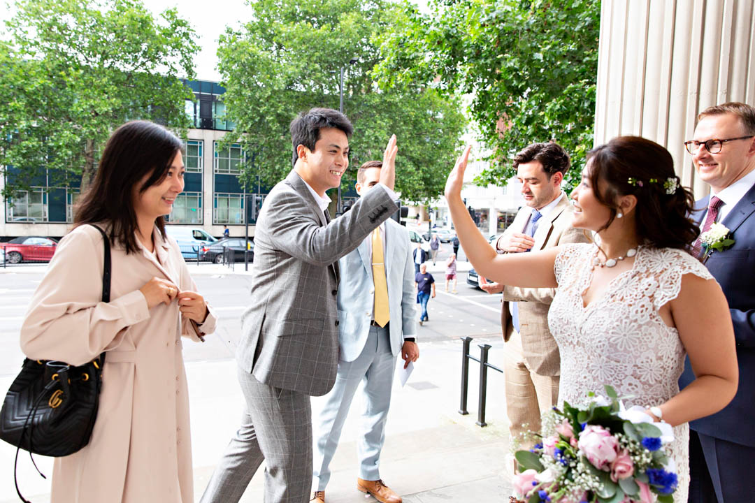 A bride high-fives one of her guests as they mingle before their small wedding in the Paddington Room.
