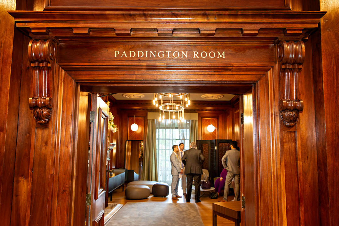A photograph showing the ornately door frame entrance to the Paddington Room. Through the open door you can see the wedding party waiting for the ceremony to commence.