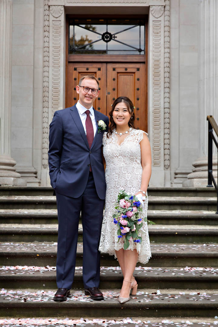 A bride and groom strike a relaxed pose on the steps of the register office, after their wedding ceremony in the Paddington Room.