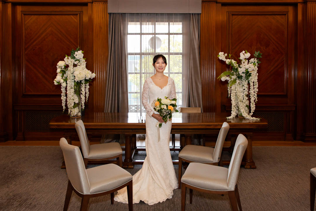 A bride in a full length lace gown poses for a quick portrait in the Westminster Room, ahead of her ceremony in one of the rooms next door.