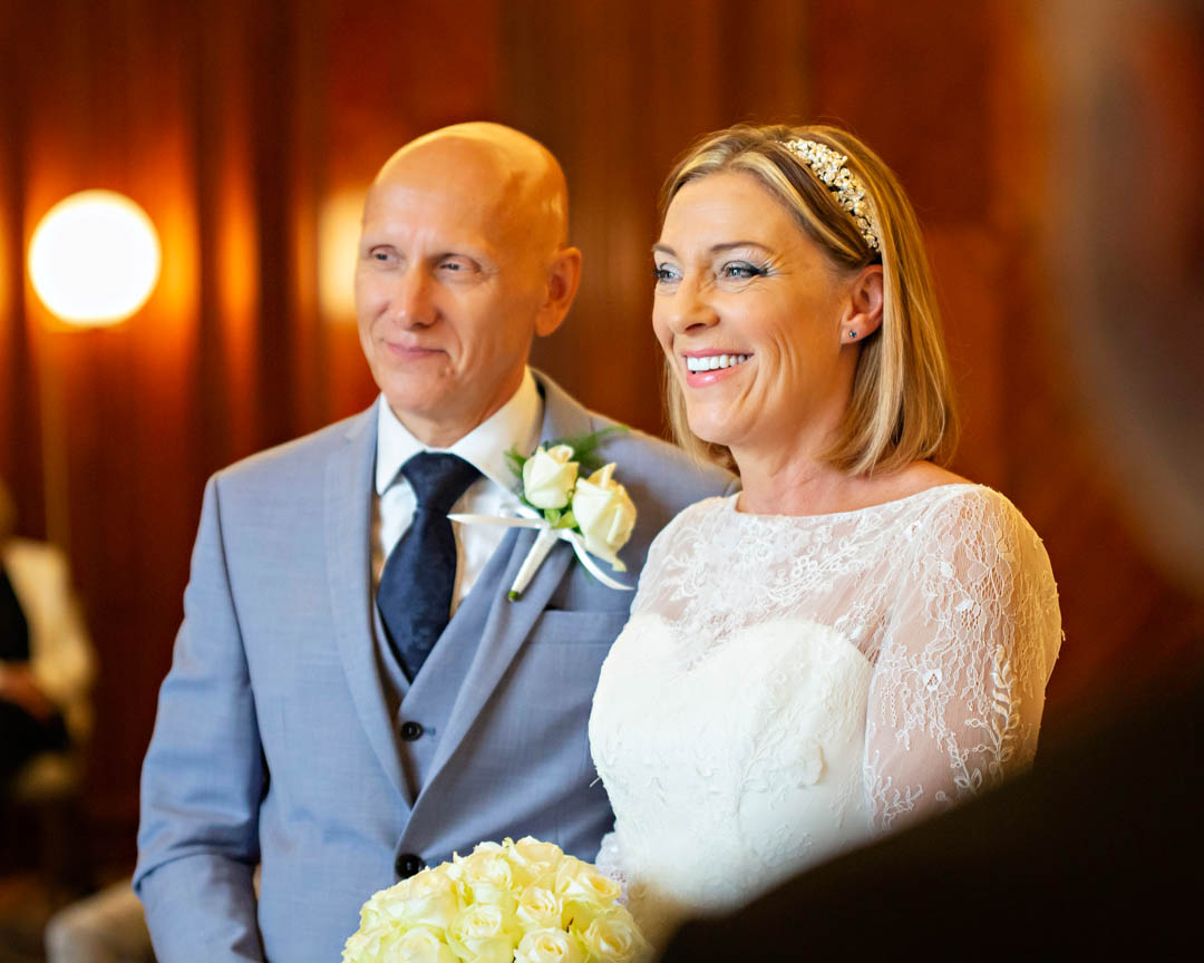 An intimate, candid image of the bride and groom as the bride confirms her name for the registrar during this civil wedding ceremony in the Westminster Room.
