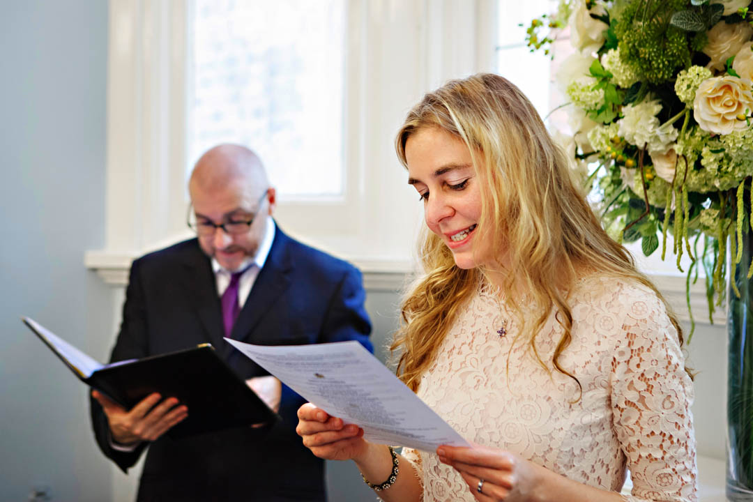 A guest stands at the front of the ceremony room to give a wedding reading for the bride and groom.