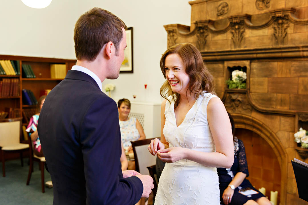A bride gets the giggles as she's about to put the wedding ring on the groom's hadn't during an intimate civil wedding with Westminster registrars.