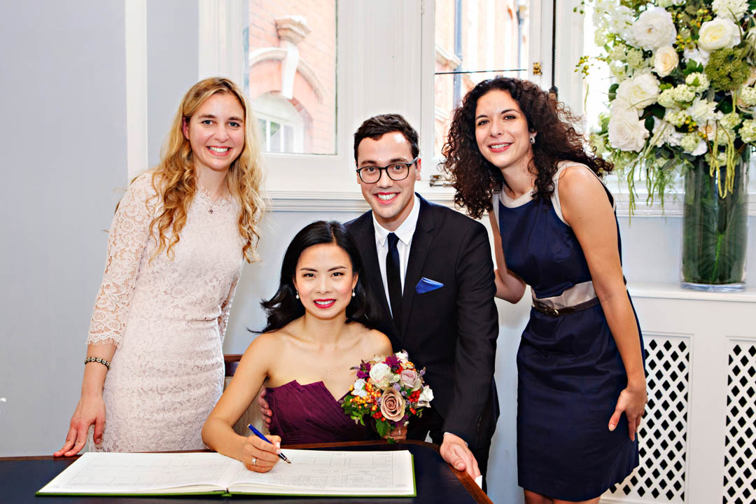 A bride and groom pose with their wedding witnesses after signing the wedding register. The super elegant bride is wearing a purple strapless dress.