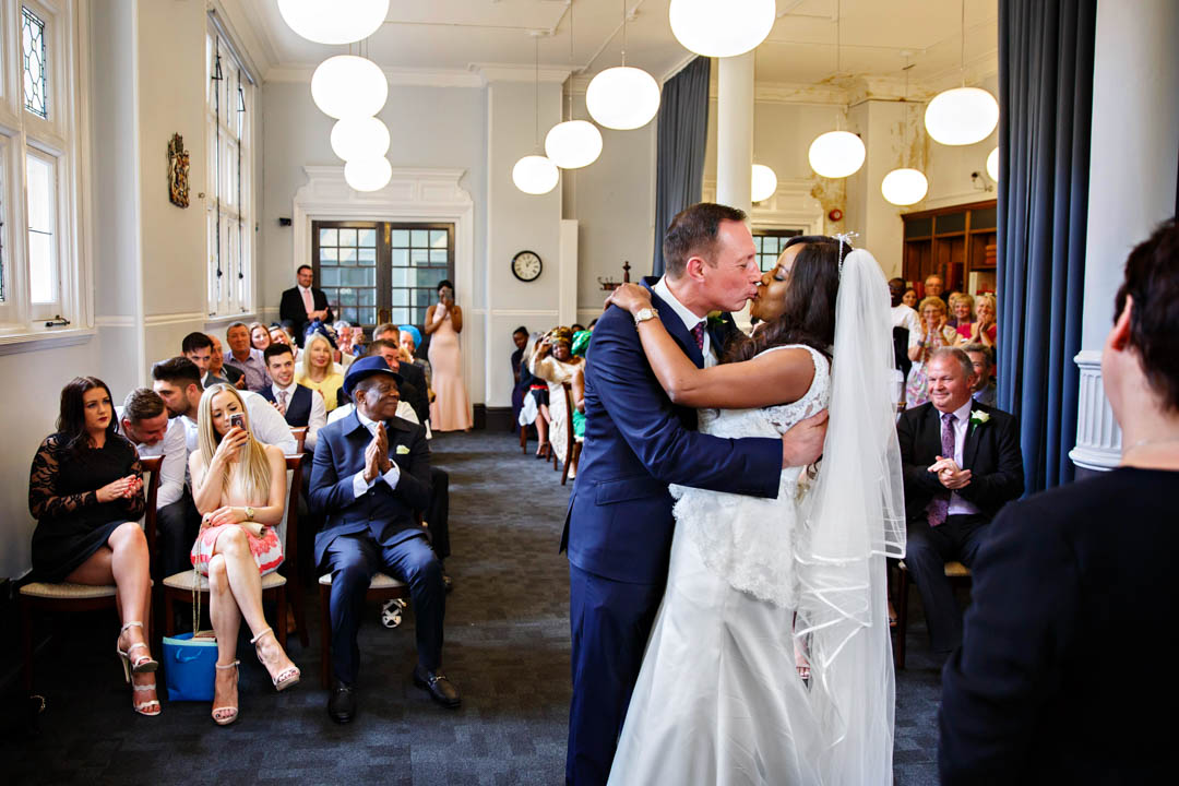 A bride and groom kiss passionately as they are announced as husband and wife at the end of their register office wedding at Mayfair Library.